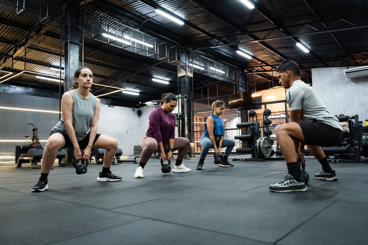 Small group performing kettlebell squats during a supervised fitness session