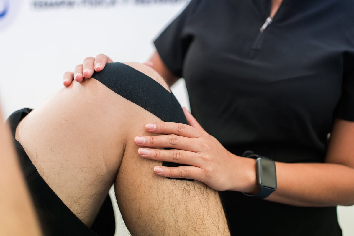 Physiotherapist applying kinesiology tape to a patient's knee