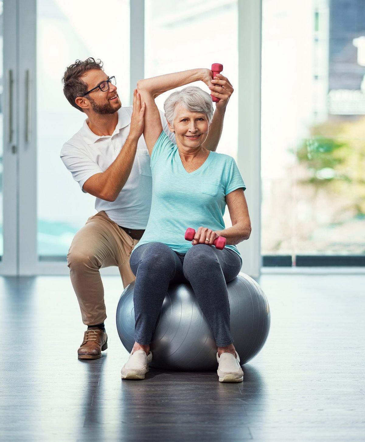 Physiotherapist supporting a senior patient through rehabilitation at home